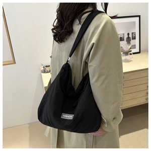 Detail of a large black waterproof crossbody bag with a fashion logo patch and nylon texture