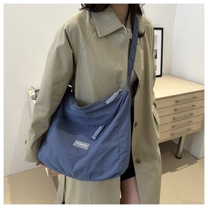 Detail of blue high-capacity nylon tote bag featuring adjustable strap and fashion label