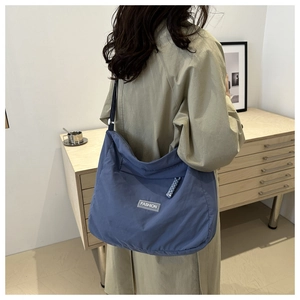 Detailed view of spacious smog blue nylon tote bag with Fashion tag worn by a model