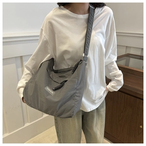 Detailed view of gray nylon crossbody bag with adjustable strap and fashion label detail