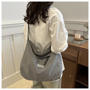 Grey nylon tote bag worn by model in a minimalist home setting showing casual style