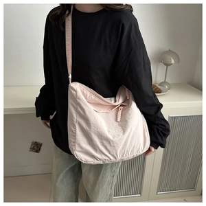 Close-up of light pink nylon tote bag featuring a minimalist FASHION brand label detail