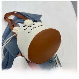 Detail of bucket bag showing canvas and leather stitching with drawstring closure