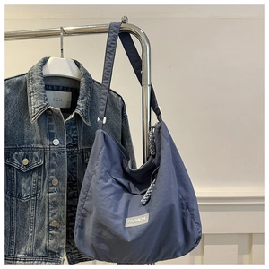 Close-up of a blue nylon tote bag with a fashion label and adjustable shoulder strap