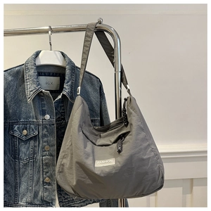 Detail of grey nylon crescent crossbody bag with waterproof fabric and fashion label