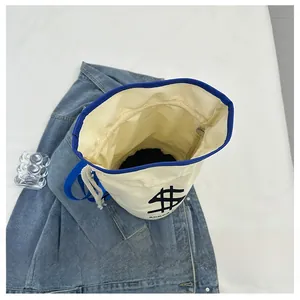 Detail view of the drawstring bucket bag interior with blue trim and dollar sign print