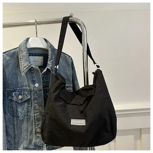 Detailed macro view of black nylon hobo bag featuring a white Fashion label and wide strap