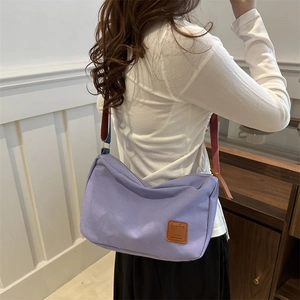 Purple canvas crossbody bag with colorful wide strap shown on model for daily use