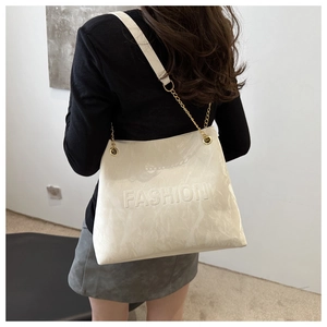Detailed shot of white marble pattern tote bag with golden chain strap and fashion logo
