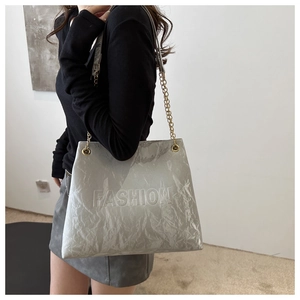 Detail of silver tote bag with pleated texture and embossed fashion lettering