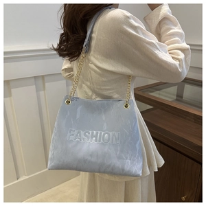 Detail of light blue marble texture handbag with embossed FASHION logo and gold chain