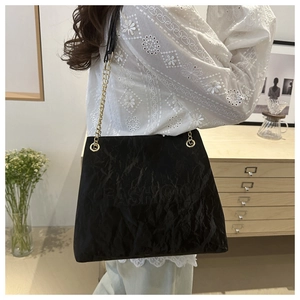Detail of black wrinkled texture tote bag with FASHION embossed letters and gold chain strap