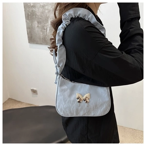 Detail of light blue pleated shoulder bag with silver butterfly buckle on a model