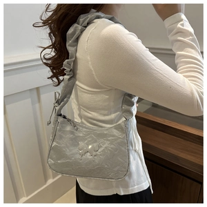 Silver crescent shoulder bag featuring ruched texture and metallic butterfly detail