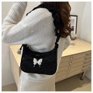 Detail of black crescent shoulder bag with silver butterfly buckle and ruched handle strap