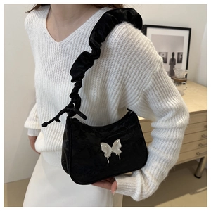 Detail of black crescent shoulder bag featuring silver butterfly logo and ruched strap