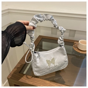 Detail of silver pleated crescent bag with a gold butterfly logo and ruffled shoulder strap