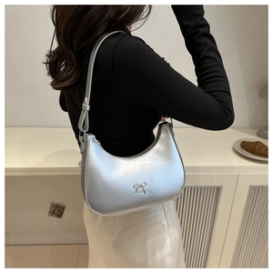 Silver crescent underarm bag featuring a metallic finish and a metal bow detail on a model