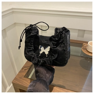Close-up of black pleated underarm bag featuring a silver metal butterfly ornament
