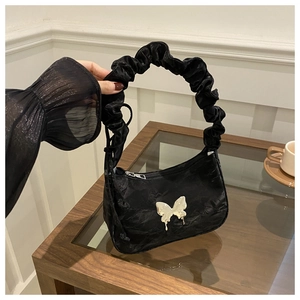 Close-up of black crescent bag with metallic silver butterfly and ruched handle detail