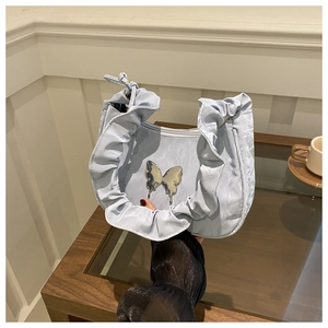 Close-up of light blue ruffled hobo bag featuring a silver metal butterfly buckle detail