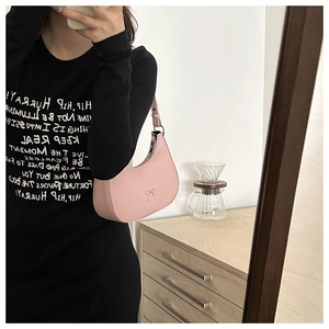 Detailed view of pink leather hobo bag with silver bow buckle on model's shoulder