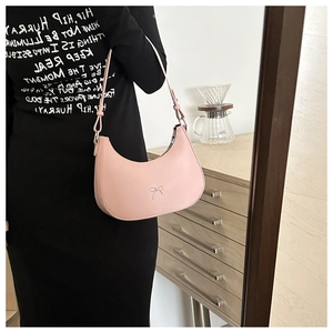 Detail of light pink hobo bag with silver bow buckle worn over a black dress