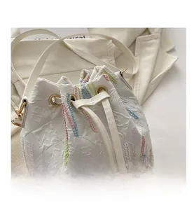 Detail of white embossed bucket bag featuring colorful vertical stripes and drawstring