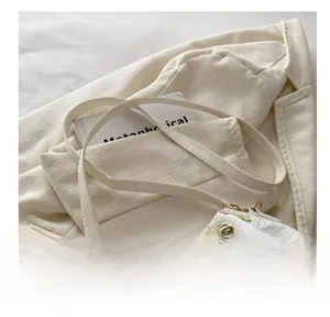 Detailed view of floral embroidery and gold metal hardware on a white nylon bucket bag