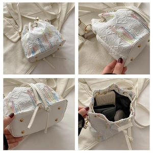 Detail of white bucket bag with colorful embroidery and metal base studs for wear protection