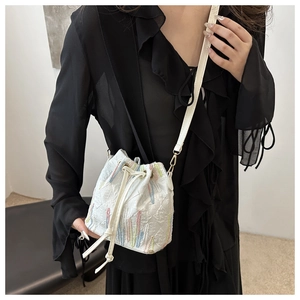 Detailed shot of white quilted nylon bucket bag with colorful tassel embroidery