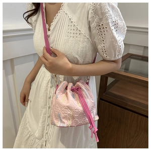 Detail of pink drawstring bucket bag with embossed floral patterns and embroidery