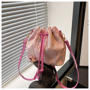 Detail of pink drawstring bucket bag showing textured fabric and adjustable strap