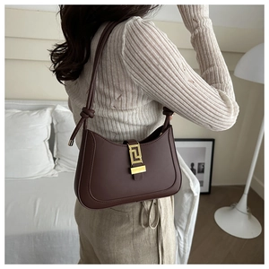 Detail of coffee brown underarm bag with gold geometric buckle and matte leather texture