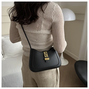 Detail of minimalist black matte leather bag with golden geometric clasp and strap