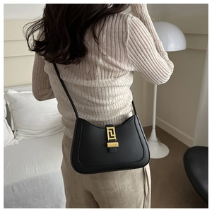 Close-up of the elegant black leather crescent bag featuring a golden geometric clasp buckle