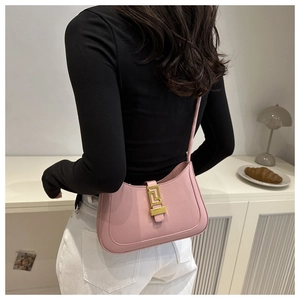 Detail of pink leather hobo bag with gold geometric buckle on woman shoulder