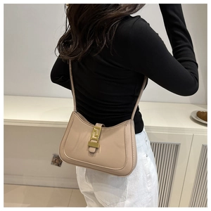 Close-up of beige hobo shoulder bag with a gold geometric metal buckle and fine stitching