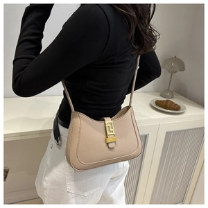 Detail of beige leather crescent bag with unique gold geometric clasp and stitching