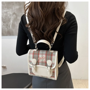 Close-up of a plaid backpack with bow embroidery and silver buckles on a model