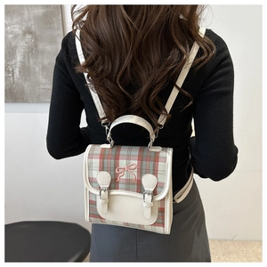 Close-up of British plaid backpack with beige leather trim and pink bow embroidery detail