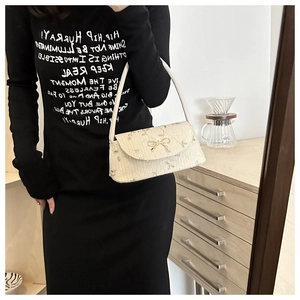 Détail d'un sac tressé avec broderie florale et ornement papillon en métal doré chic