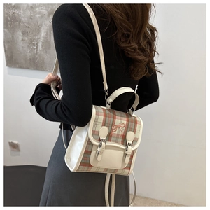Detail of red and green plaid backpack featuring bow embroidery and cream white straps