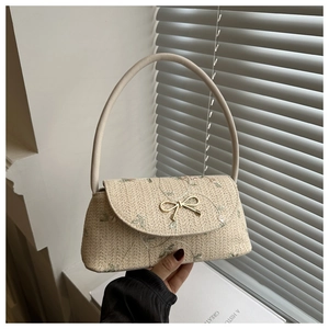 Détail du sac à bandoulière en paille avec nœud métallique et broderie florale