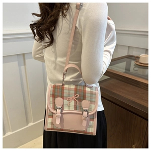 Detailed view of pink plaid crossbody bag with bow embroidery and buckle straps