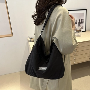 Minimalist black large capacity tote bag with fashion tag worn by a model in a room