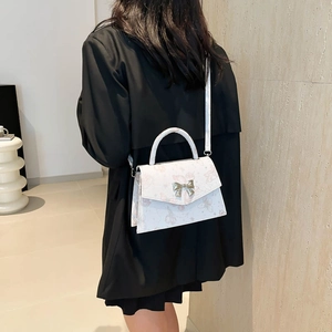 Chic white tote bag with pink butterfly prints and gold bow buckle, shown on model