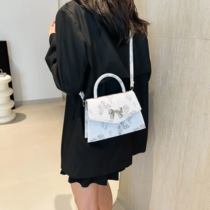 White floral tote bag with silver bow clasp shown on a model in a minimalist setting