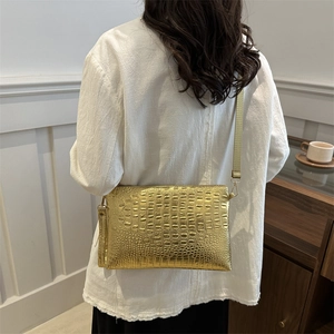 Golden embossed crocodile pattern rectangular crossbody bag with slim strap on a model
