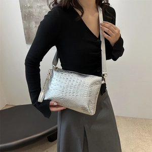 Silver crocodile pattern handbag with detachable shoulder strap shown in a minimalist setting